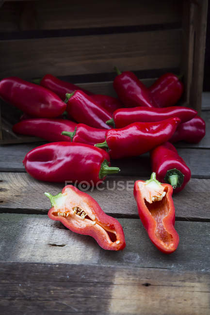 Chopped red pointed peppers, halved, on wood — Stock Photo