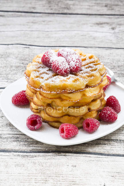 Pila De Waffles Con Frambuesas Y Azucar Glas Rociado Estudio