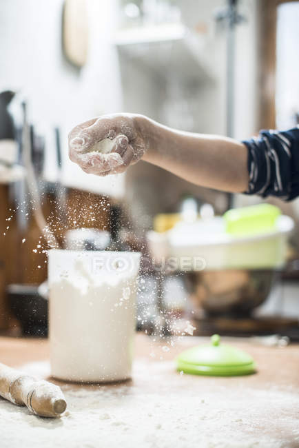 Vue recadrée de la main dispersant la farine sur le plan de travail de la cuisine — Photo de stock