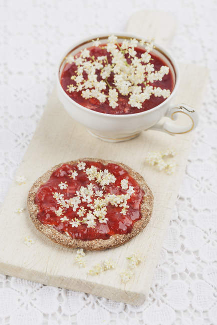 Crispbread with homemade strawberry jam elderflowers — Stock Photo