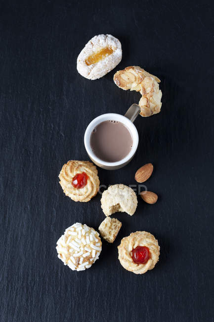 Diversi tipi di biscotti alla mandorla italiani e una tazza di cacao su ardesia — Foto stock