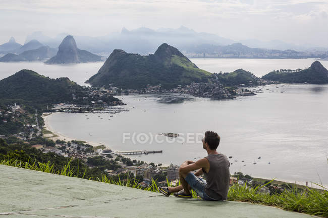 Turista sentado en el prado en el punto de vista - foto de stock
