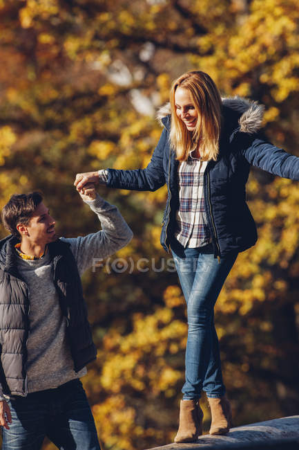 Homme aidant femme équilibrage sur le tronc — Photo de stock