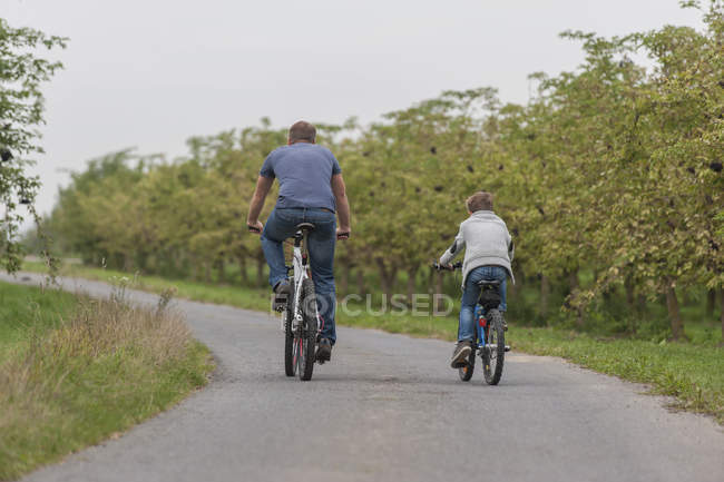 Back view of little boy and his father on bicycle tour — Stock Photo