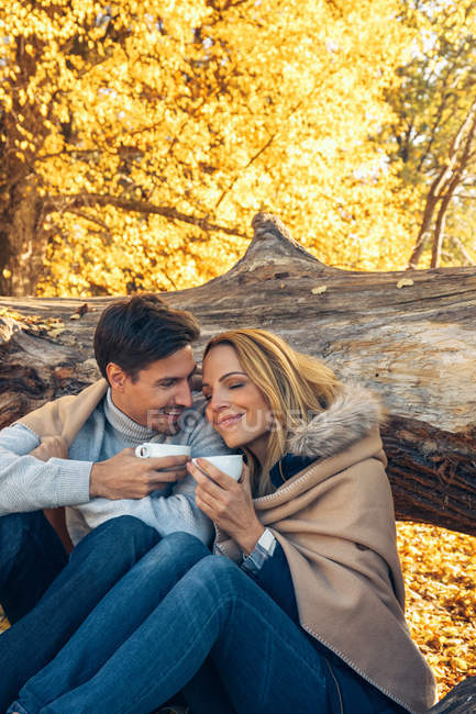 Paar hält Tassen im Herbstwald — Stockfoto