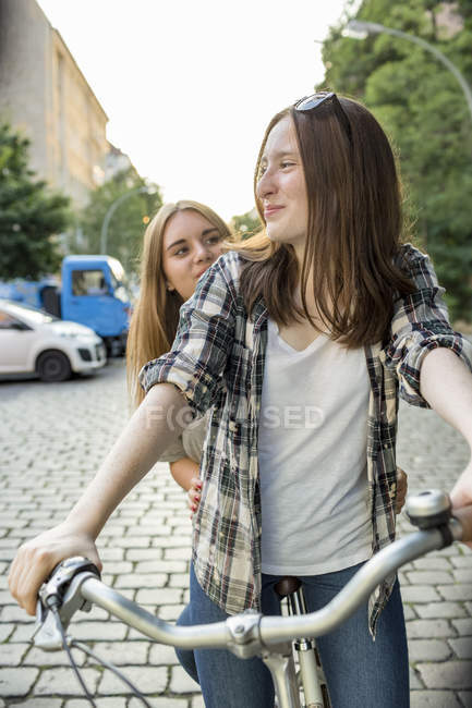 Two teenage girls together on a bicycle — Stock Photo