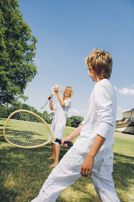 Frau spielt an einem Sommertag im Park mit ihrem Sohn Tennis — Stockfoto
