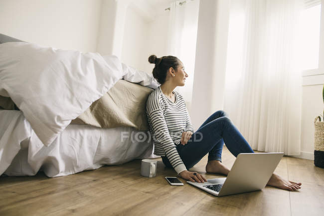 Donna seduta in camera da letto e utilizzando il computer portatile — Foto stock