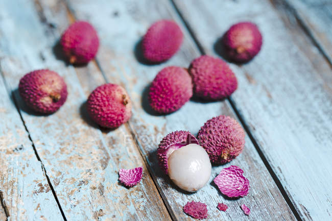 Whole and peeled lychees on light blue wood — Stock Photo