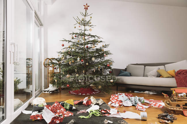 Living room on Christmas morning with torn up wrapping paper in front of the tree — Stock Photo