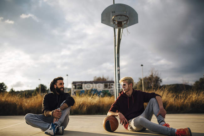Мужчины сидят на баскетбольной площадке — стоковое фото