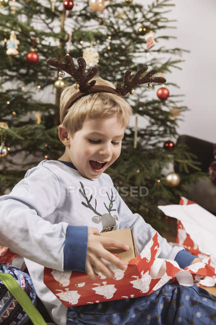 Little boy unwrapping a Christmas gift at home — Stock Photo