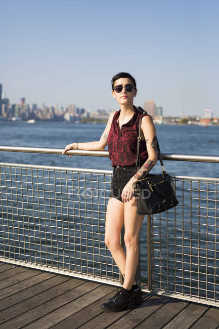 USA, New York City, Williamsburg, tätowierte junge Frau lehnt an einem Geländer — Stockfoto