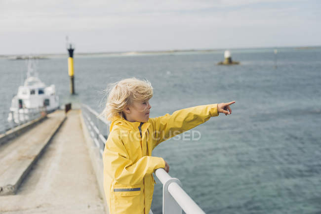 Francia, Bretagna, Roscoff, ragazzo con l'impermeabile giallo al porto che punta con il dito — Foto stock