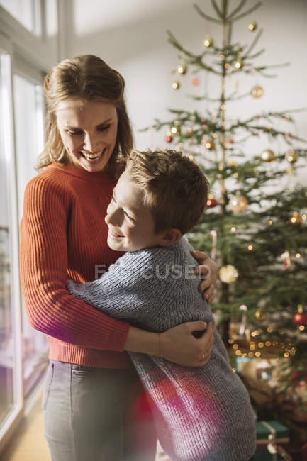 Happy mother and son hugging by Christmas tree — Stock Photo