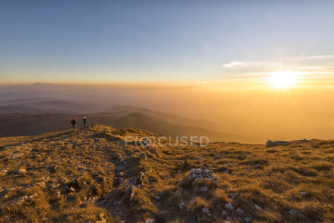 Italia, Marche, Monte San Vicino, due escursionisti che guardano al tramonto — Foto stock