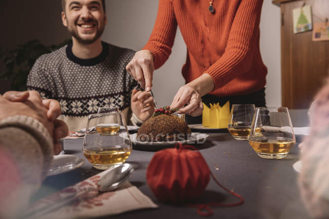 Christmas pudding is being cut on family table — Stock Photo