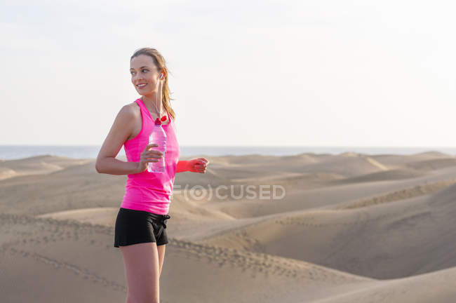 Young woman jogging on the beach, taking a break — Stock Photo