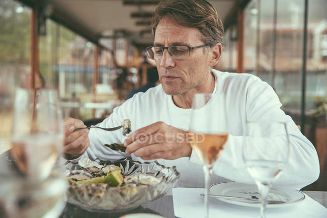 Brazil, Florianopolis, man eating fresh oysters in a restaurant — Stock Photo