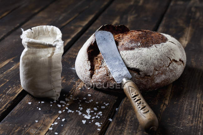 Pain croustillant avec couteau et grains de sel — Photo de stock