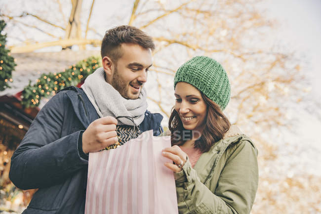 Пара на Рождественской ярмарке с подарочной сумкой — стоковое фото