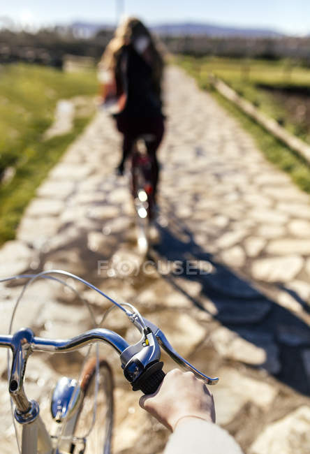 Cropped image of two women riding bicycle along a path — Stock Photo