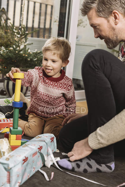 Vater und Sohn spielen mit Bauklötzen vor dem Weihnachtsbaum — Stockfoto
