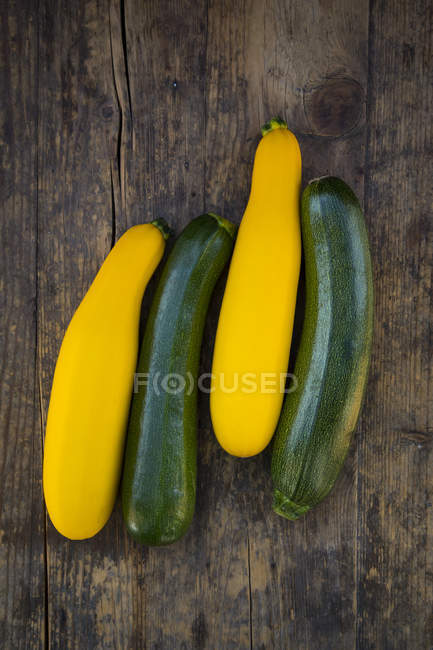Calabacín verde y amarillo fresco sobre madera oscura - foto de stock