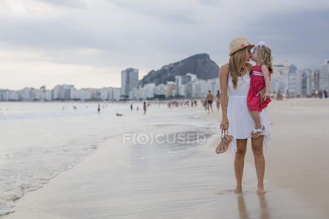 Brésil, Rio de Janeiro, mère portant et embrassant fille sur la plage de Copacabana — Photo de stock
