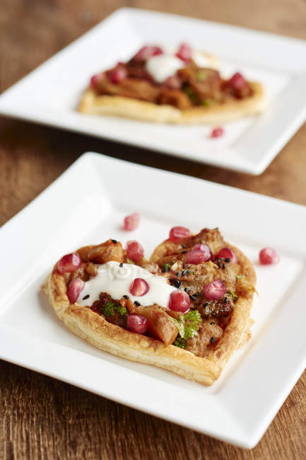 Heart shaped puff pastry tarts with eggplant and pomegranate arils — Stock Photo
