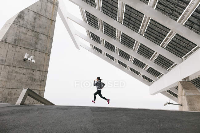 Femme jogging sous panneau solaire — Photo de stock