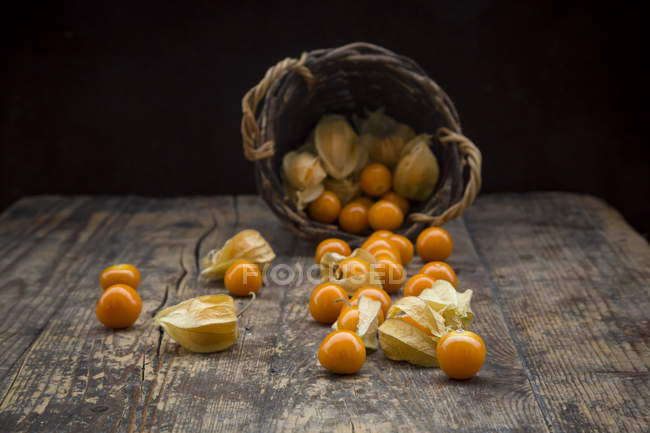 Physalis in cesto di vimini e su superficie di legno — Foto stock