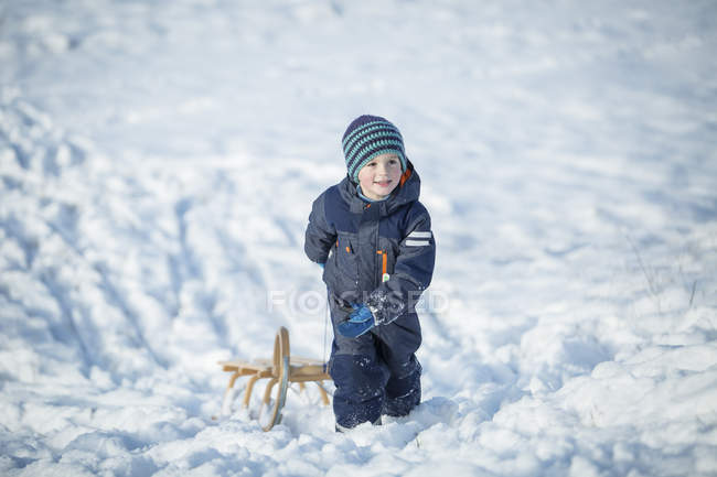 Мальчик с санями зимой — стоковое фото