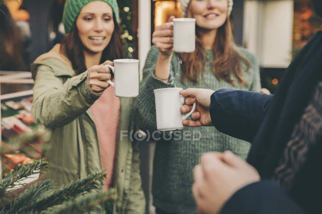 Щасливі друзів дзвінкою чашки гарячий пунш на Різдвяний ярмарок — стокове фото