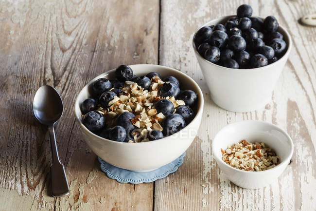 Bowls of porridge with blueberries on wood — Stock Photo