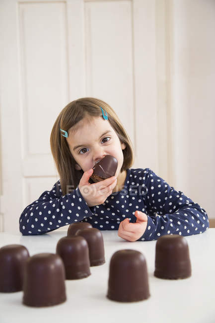 Portrait of little girl eating chocolate marshmallows — Stock Photo