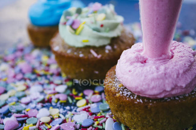 Bolsa de hielo decorando un cupcake con crema rosa, primer plano - foto de stock