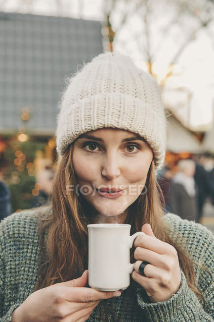Mujer teniendo caliente ponche en el mercado de Navidad - foto de stock