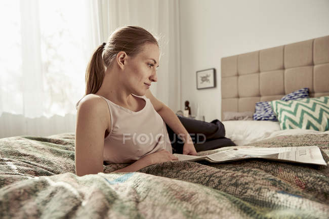 Woman reading newspaper in bedroom — Stock Photo
