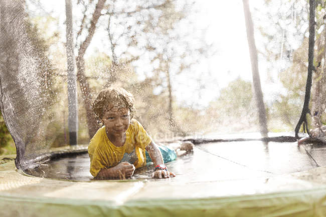 Sorrindo menino deitado no trampolim — Fotografia de Stock