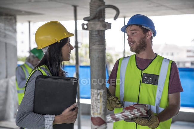 Engineer inspecting construction site, talking to workers — Stock Photo
