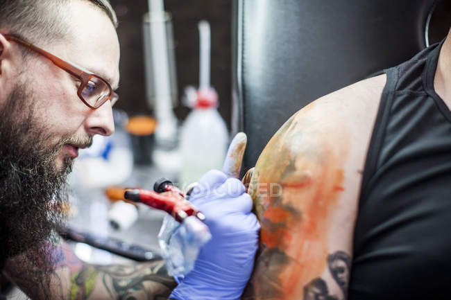 Close-up de tatuagem artista tatuagem braço — Fotografia de Stock