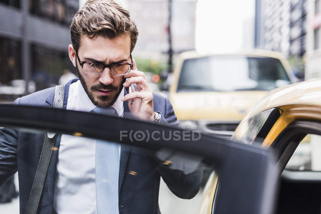 Бізнесмен в Манхеттені на мобільний телефон, ввівши таксі, Нью-Йорк, США — стокове фото