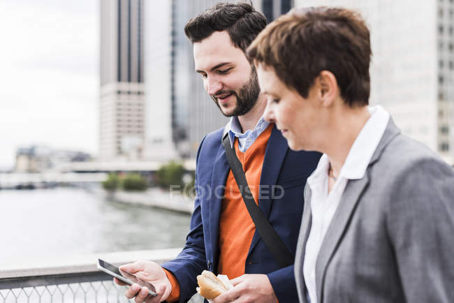 Business people talking outdoor and sharing mobile phone — Stock Photo