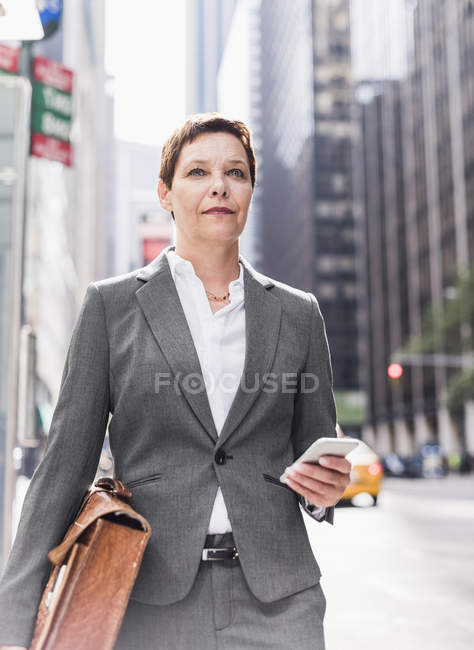 Femme d'affaires marchant à Manhattan avec téléphone portable, États-Unis, New York — Photo de stock