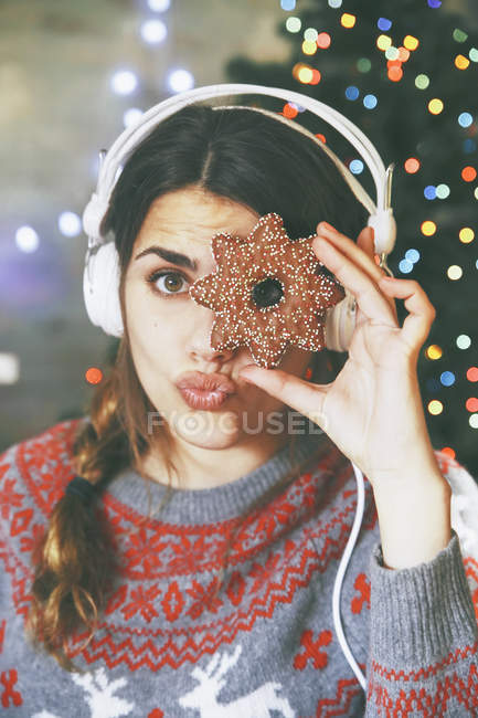 Frau mit Kopfhörer blickt durch ein Weihnachtsgebäck — Stockfoto