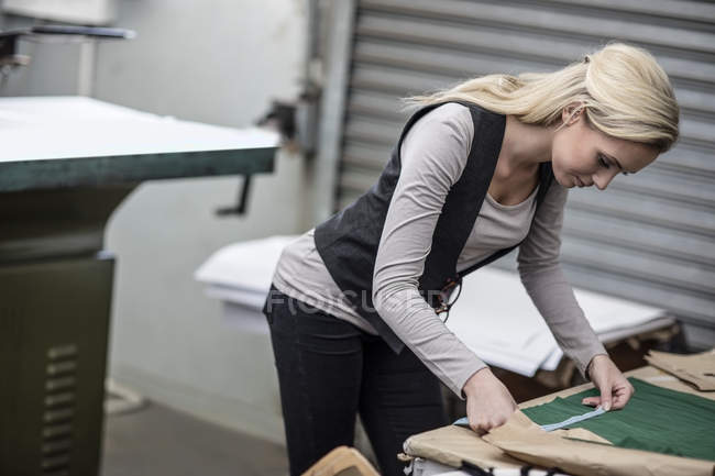 Jeune femme travaillant avec ruban à mesurer dans un atelier de tailleur — Photo de stock