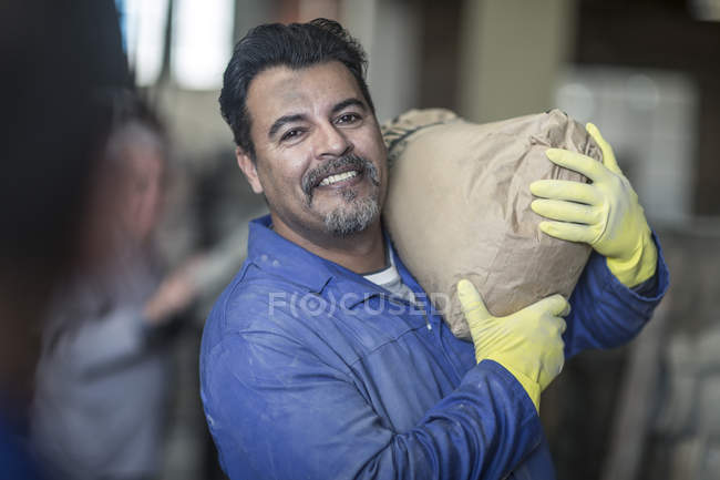 Travailleur portant sac dans une usine industrielle — Photo de stock
