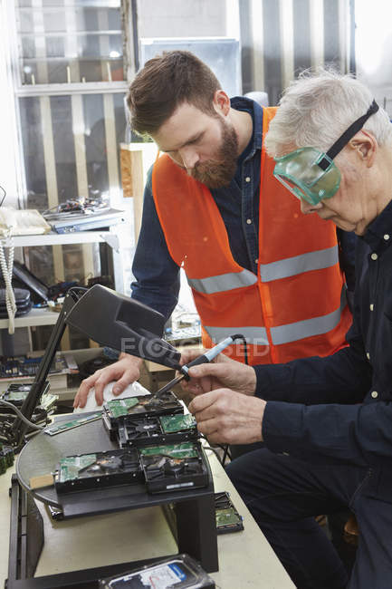 Lavoratori in impianti di riciclaggio di computer smantellamento del disco rigido — Foto stock