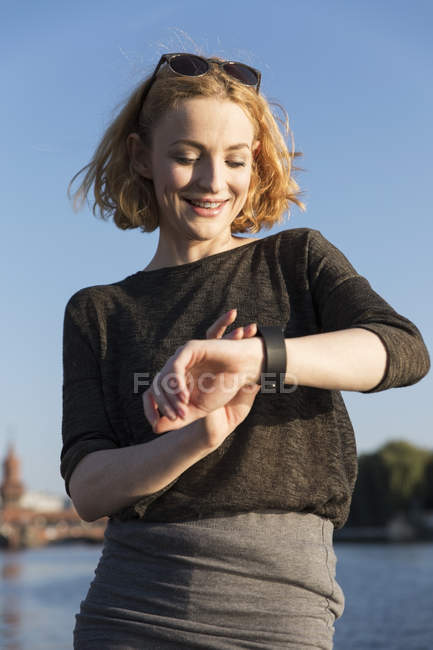 Jeune femme blonde attrayante regardant smartwatch — Photo de stock